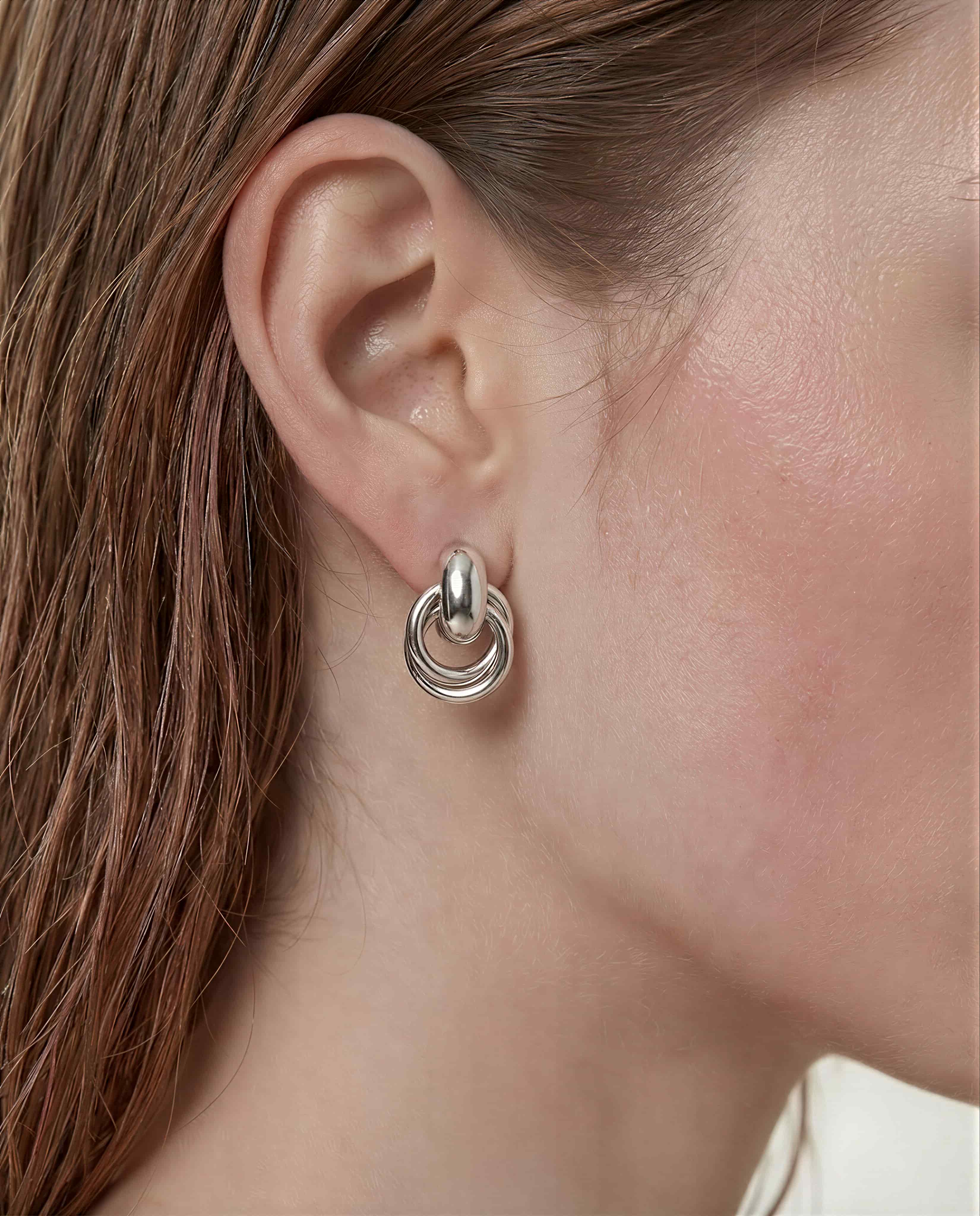Sculpted interlock drop earrings in 925 silver plated finish featuring smooth polished layered loop design.