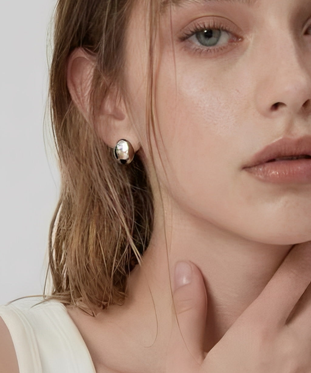 Model wearing soft oval dome stud earrings in polished silver with a minimalist modern design by About Ease