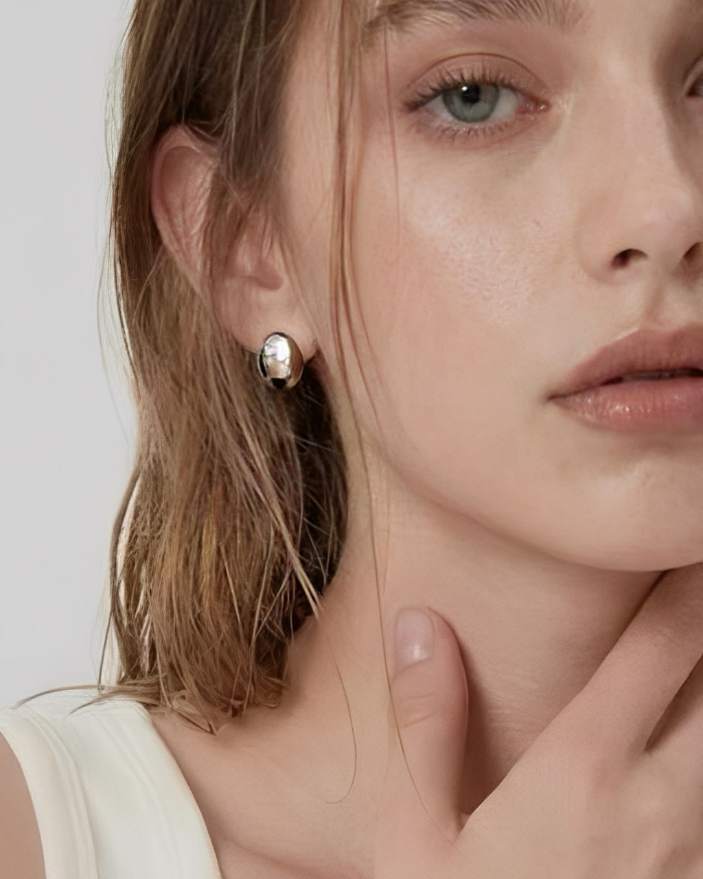 Model wearing soft oval dome stud earrings in polished silver with a minimalist modern design by About Ease