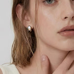 Model wearing soft oval dome stud earrings in polished silver with a minimalist modern design by About Ease