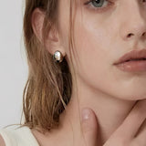 Model wearing soft oval dome stud earrings in polished silver with a minimalist modern design by About Ease