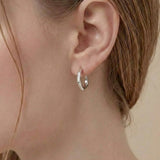 Model wearing Contour Twist Hoop Earrings in platinum plated finish with a softly contoured polished design.
