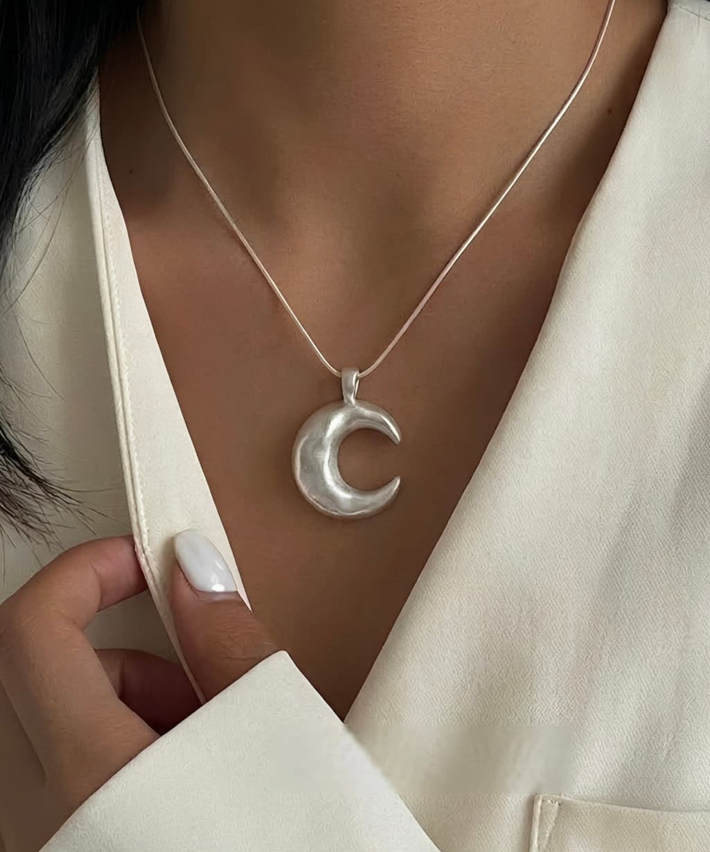 Minimalist crescent moon necklace worn on neckline with modern lunar pendant design.
