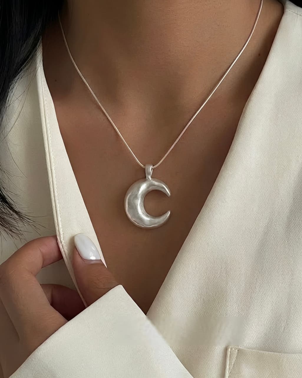 Minimalist crescent moon necklace worn on neckline with modern lunar pendant design.
