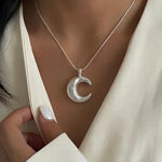 Minimalist crescent moon necklace worn on neckline with modern lunar pendant design.
