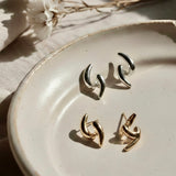 Ease Sculpted Curve Earrings in 18K gold and 925 silver plated finish displayed on a ceramic plate with soft natural lighting.
