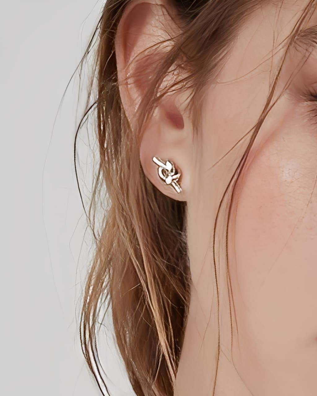 Essential Knot Stud Earrings worn on ear, minimalist knot stud earrings with a polished finish