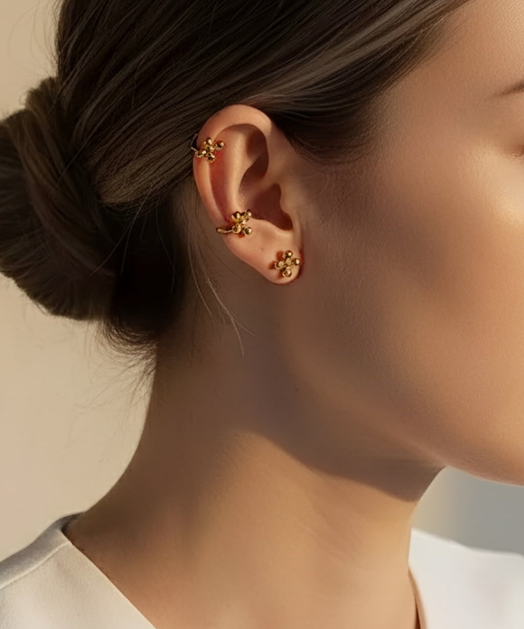 Model wearing gold cluster dot stud earrings styled as a minimalist ear stack with modern 18K gold plated ball studs and ear cuff detail.