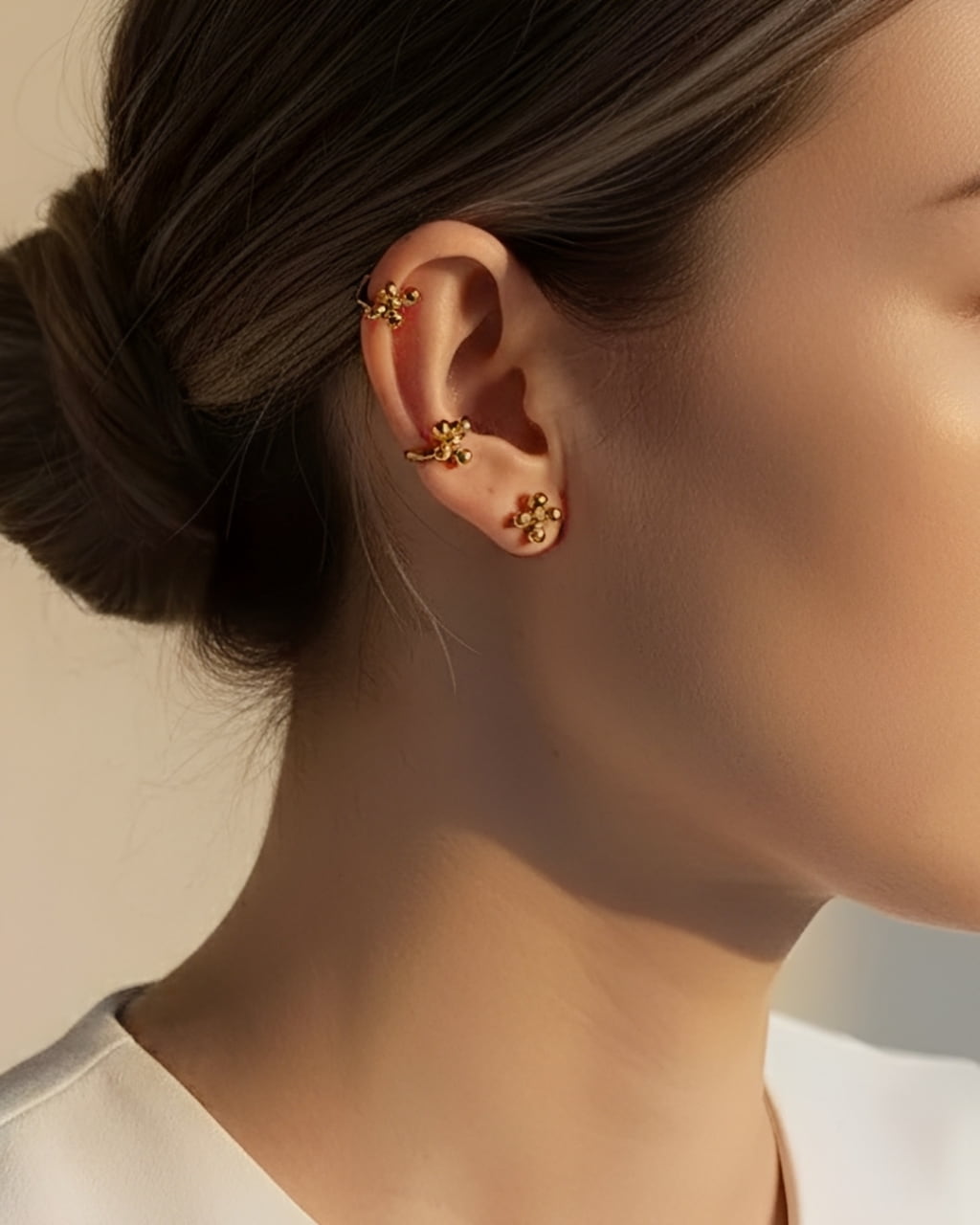 Model wearing gold cluster dot stud earrings styled as a minimalist ear stack with modern 18K gold plated ball studs and ear cuff detail.