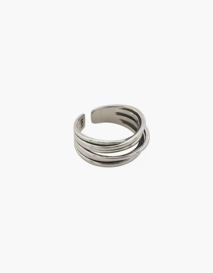 Layered Curve Ring in stainless steel with overlapping curved bands and an adjustable open design