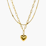 Layered gold chain necklace with polished heart pendant and linked chain detail.

