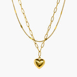 Layered gold chain necklace with polished heart pendant and linked chain detail.
