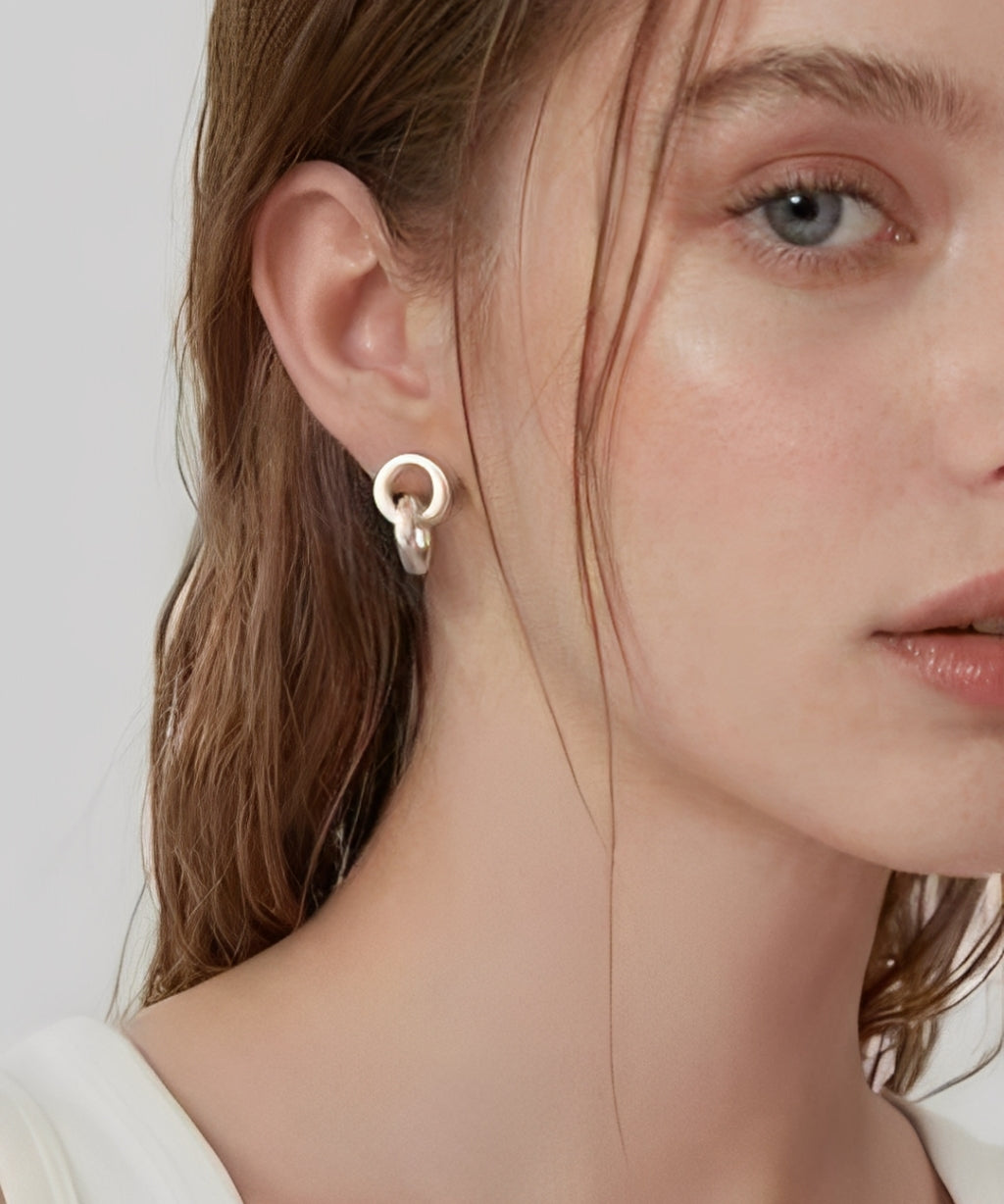 Model wearing linked form silver stud earrings with a minimalist sculptural design
