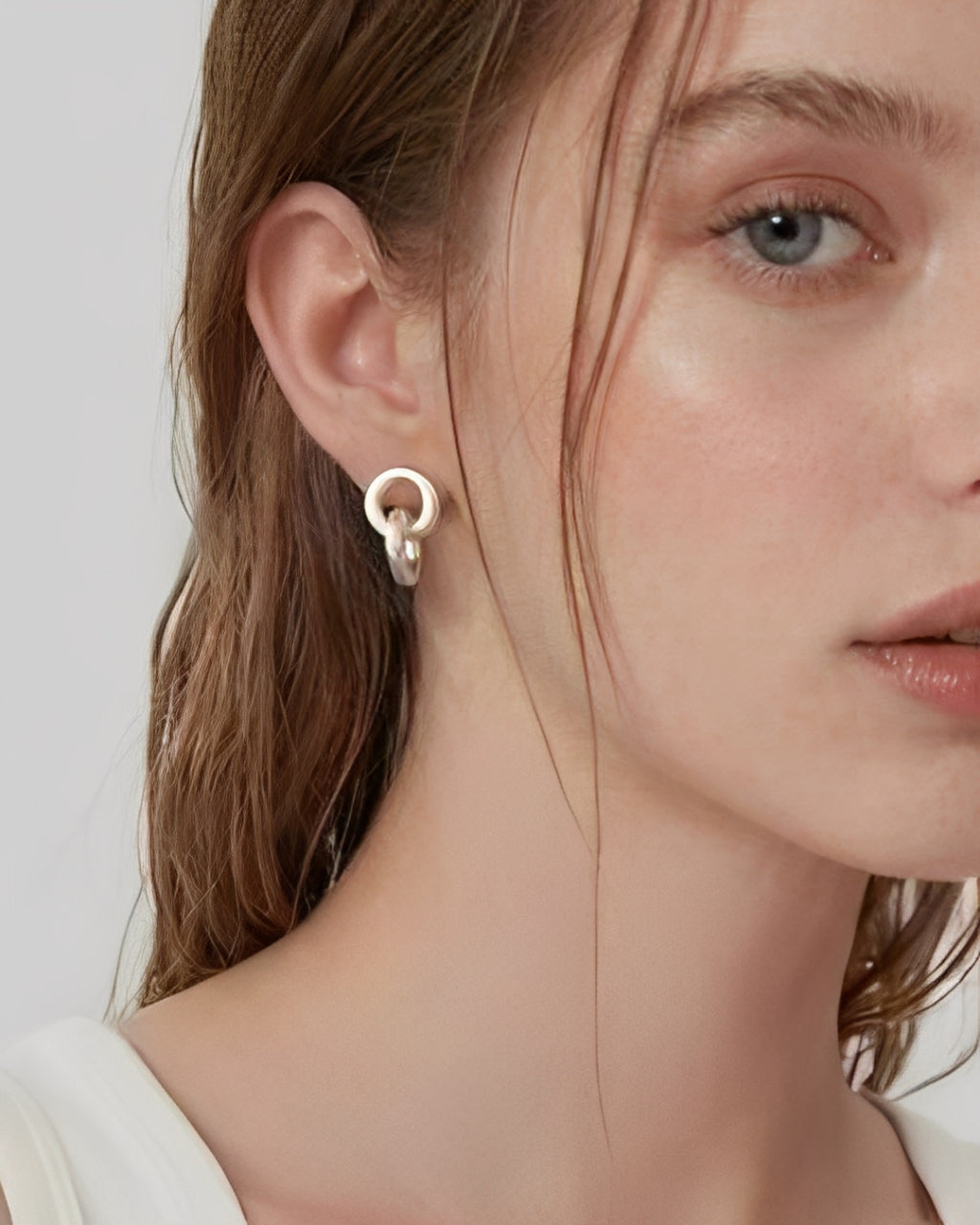 Model wearing linked form silver stud earrings with a minimalist sculptural design
