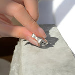 Minimal bow ring with delicate knot design shown on hand.