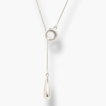 Minimal silver linear drop necklace with circular pendant and long teardrop charm.

