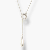 Minimal silver linear drop necklace with circular pendant and long teardrop charm.

