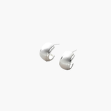 Quiet Curve Huggie Earrings in silver tone with brushed finish and polished edges, minimalist curved design.