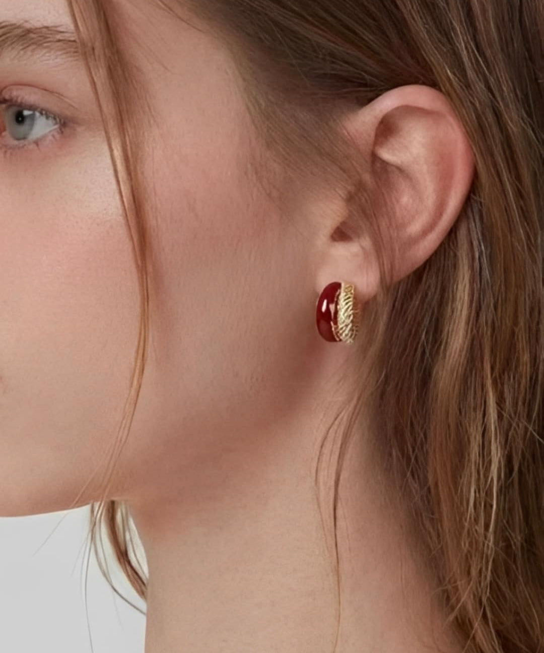 Rich Tone Huggie Earrings worn on ear, minimalist huggie earrings with a deep-toned accent and textured metal detail