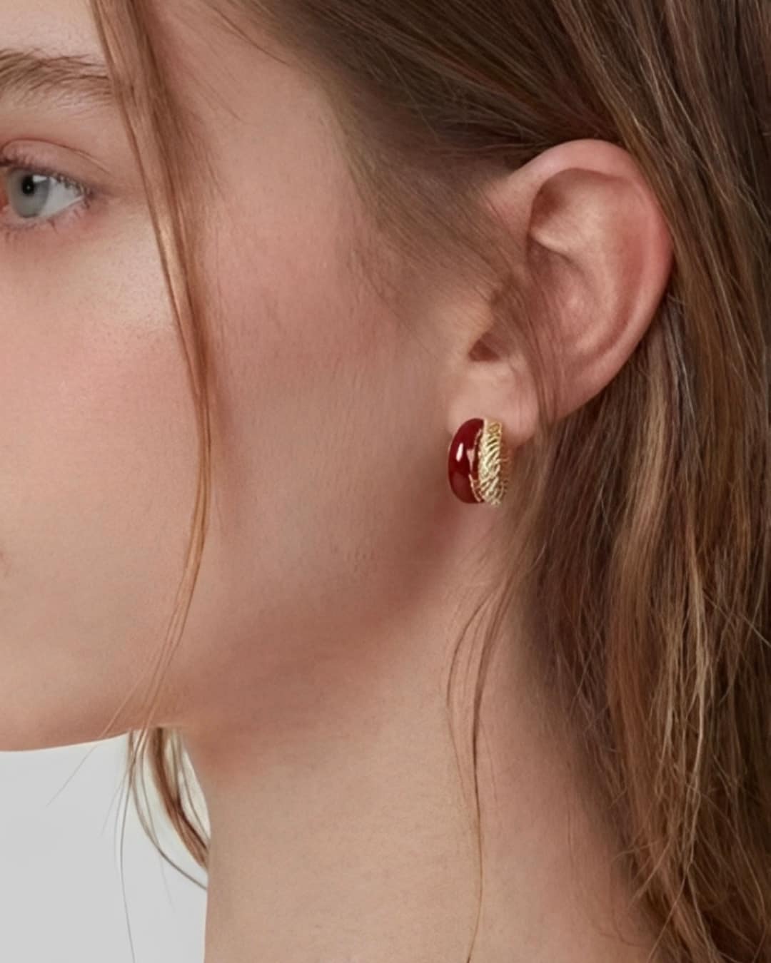 Rich Tone Huggie Earrings worn on ear, minimalist huggie earrings with a deep-toned accent and textured metal detail