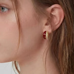 Rich Tone Huggie Earrings worn on ear, minimalist huggie earrings with a deep-toned accent and textured metal detail