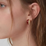 Rich Tone Huggie Earrings worn on ear, minimalist huggie earrings with a deep-toned accent and textured metal detail
