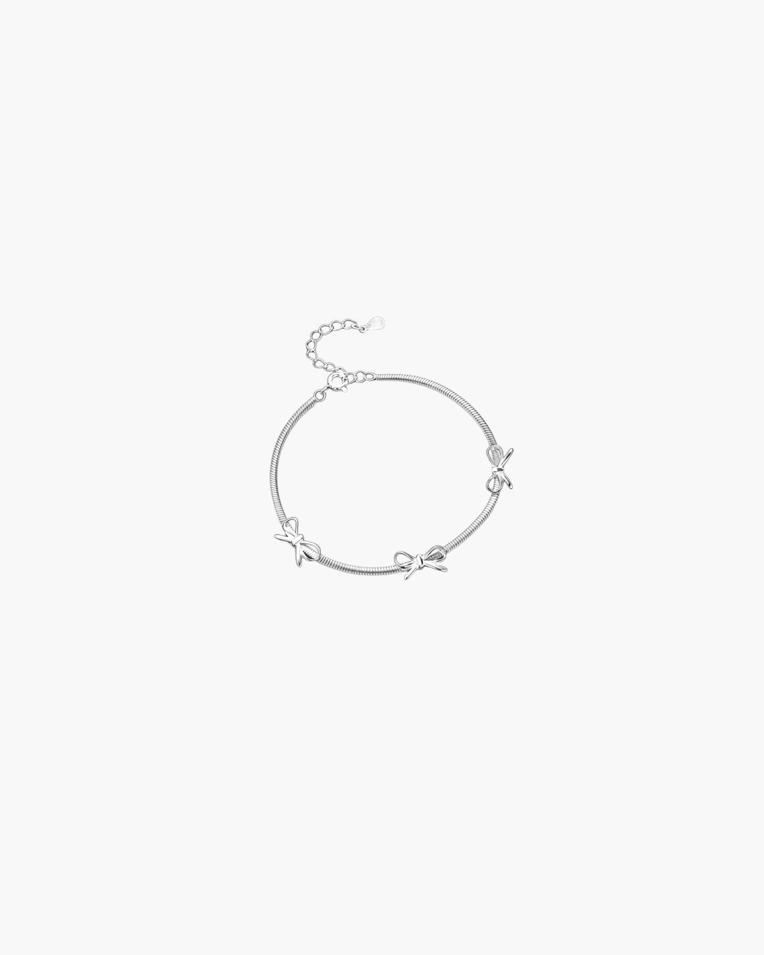 Silver ribbon accent bracelet with delicate bow details and adjustable chain closure in minimalist design.
