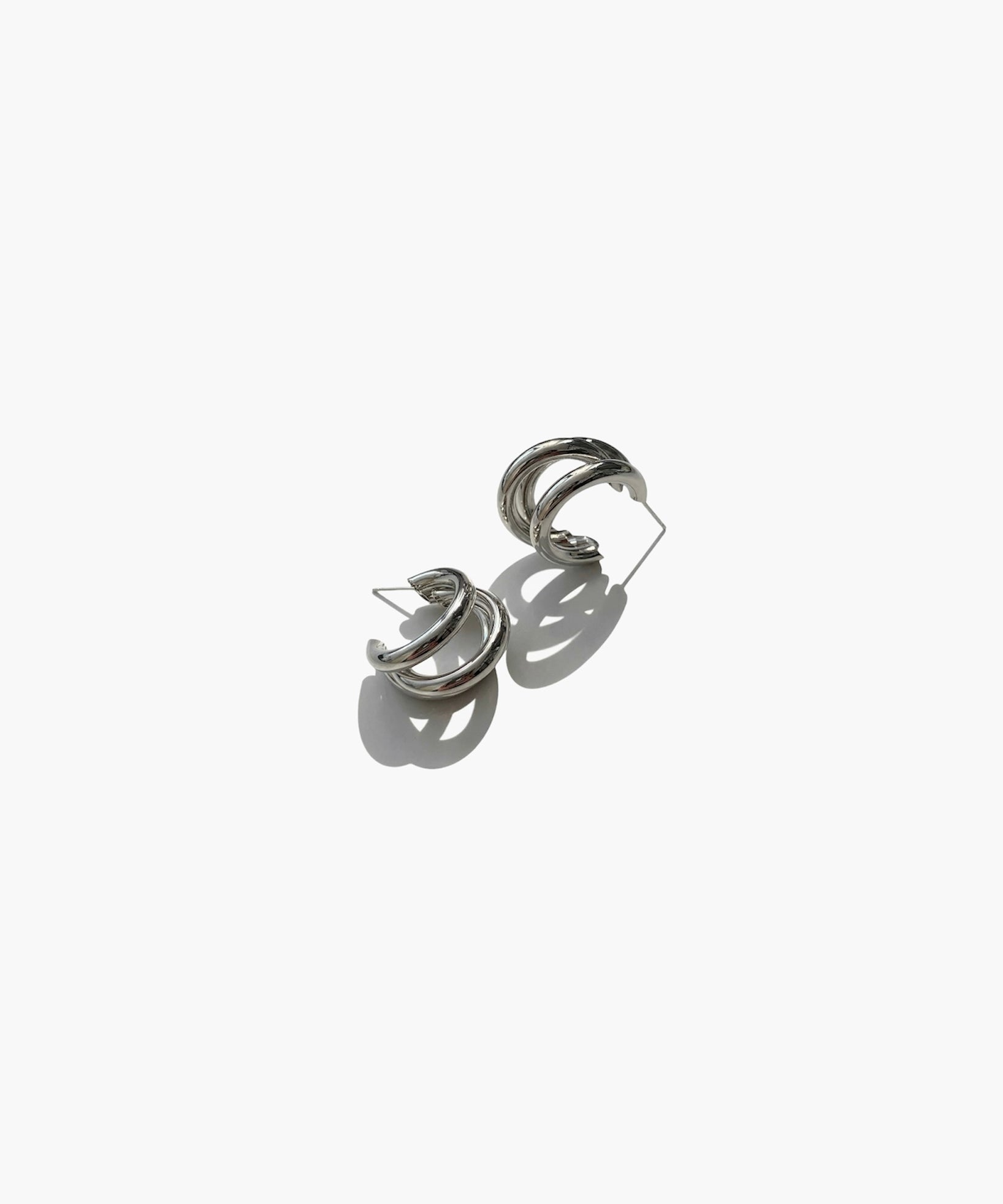Silver triple hoop earrings with minimalist modern design on white background