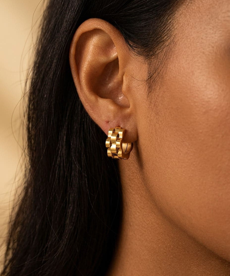 Gold wave cut hoop earrings close-up worn on ear, sculptural minimalist jewelry