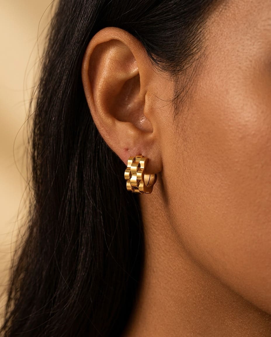 Gold wave cut hoop earrings close-up worn on ear, sculptural minimalist jewelry