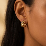 Gold wave cut hoop earrings close-up worn on ear, sculptural minimalist jewelry