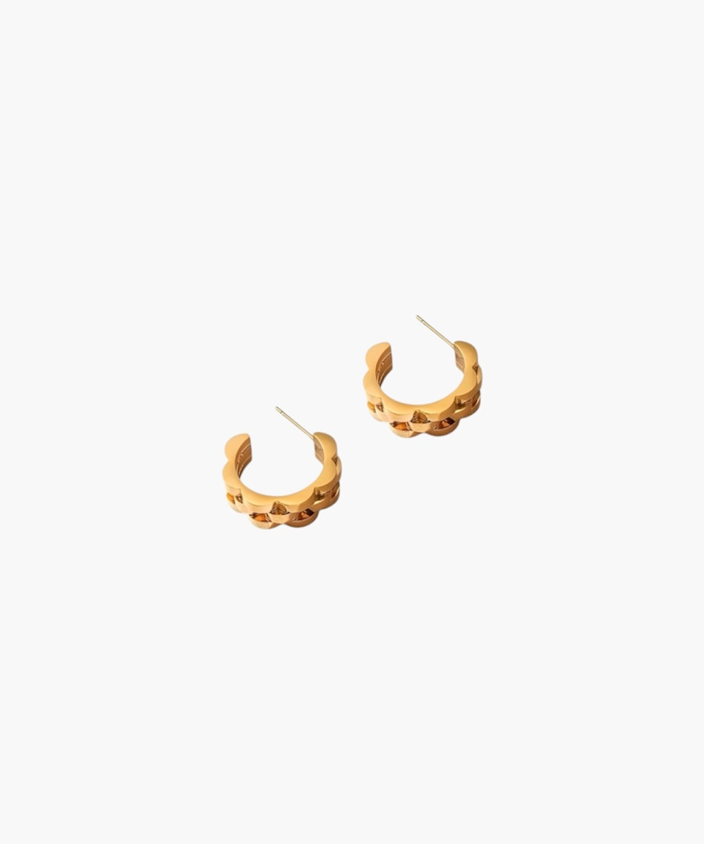 Gold wave cut hoop earrings pair on white background, sculptural minimalist jewelry