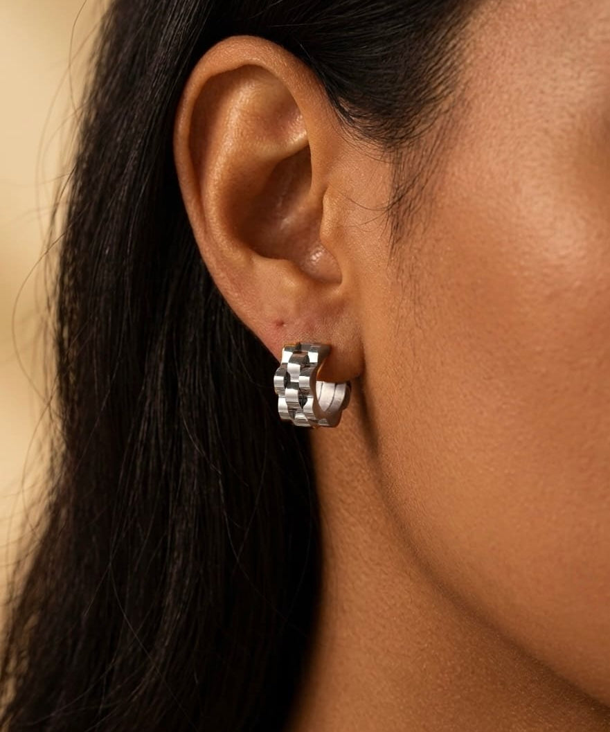 Silver wave cut hoop earrings close-up worn on ear, modern sculptural jewelry