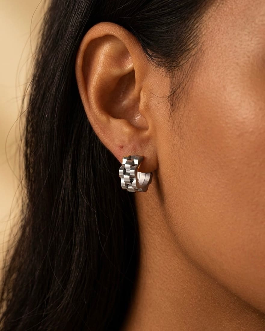 Silver wave cut hoop earrings close-up worn on ear, modern sculptural jewelry
