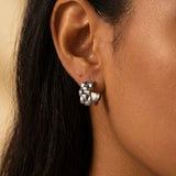 Silver wave cut hoop earrings close-up worn on ear, modern sculptural jewelry