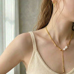 Woman wearing elegant gold pearl drop Y necklace with bar detail and pearl accent.
