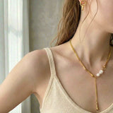 Woman wearing elegant gold pearl drop Y necklace with bar detail and pearl accent.
